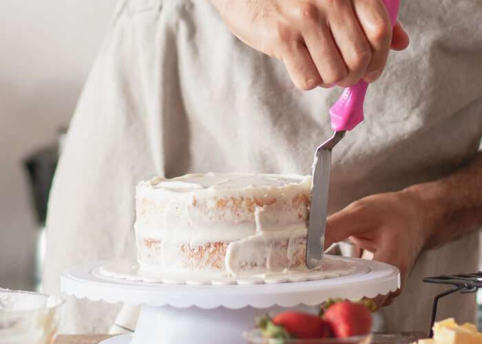 Плотную кремовую массу переложите в кондитерский мешок и сразу приступайте к выравниванию торта.
