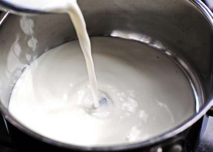 В отдельной кастрюле разогрейте кислое молоко, добавьте соль и тщательно размешайте.

