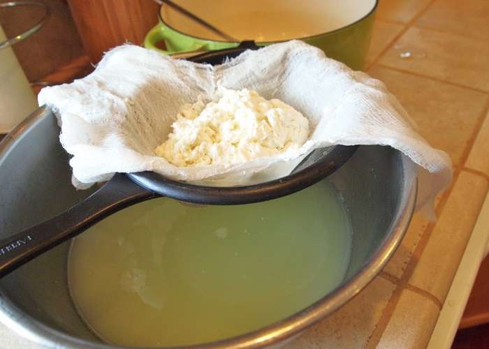 Слейте сыворотку через сито, застеленное свернутой в несколько раз марлей. Сыворотку можно использовать для выпечки.