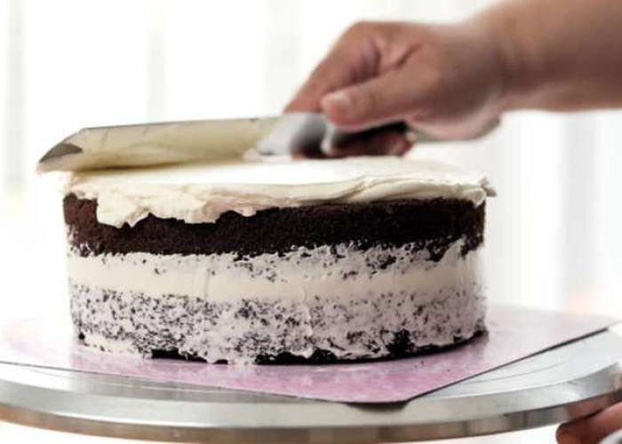 Сразу приступайте к выравниванию торта. Учтите, что заготовка должна быть холодной, а крем – комнатной температуры. Наносить его надо в два приема: сначала торт обмажьте тонким слоем и отправьте его на час в холодильник. Затем с помощью скребка и палетки выполните финишную отделку. Декорировать торт можно после двухчасовой выдержки в холодильнике.