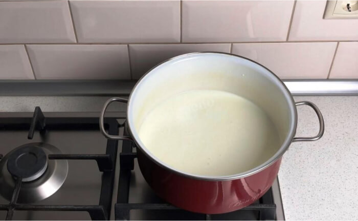 Перелейте молоко в кастрюлю, добавьте в него кефир. Перемешайте жидкость венчиком и поставьте на средний огонь для нагревания.