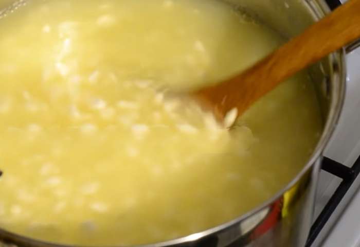 Медленно повышайте температуру сырного зерна до 42°C в течение 30 минут, периодически помешивая. Поддерживайте температуру и помешивайте зерно еще 40-45 минут. Проверьте, слипается ли зерно при сжатии, но при этом легко разделяется при растирании.