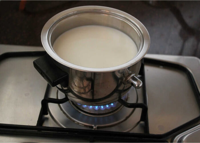 Пока стерилизуется посуда, нагрейте молоко до 40°С. Если вы используете сырье с рынка, сначала прокипятите его, а затем остудите до рабочей температуры.