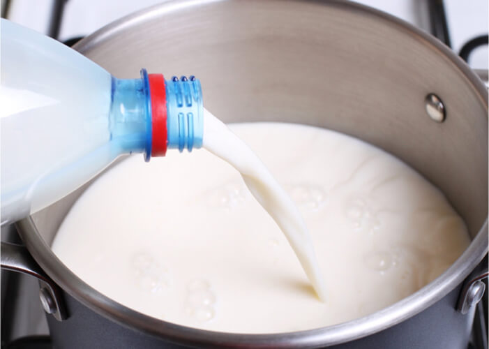 Смешайте остывшее молоко с кефиром в кастрюльке с толстым днем, подогрейте на медленном огне до температуры 35-40 градусов.