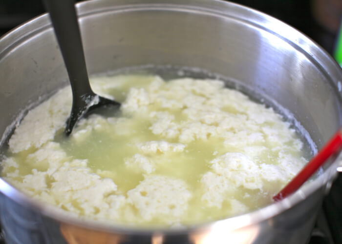 Когда молоко начнет расслаиваться на желтоватую сыворотку и белые хлопья, маленькую емкость нужно убрать с плиты.