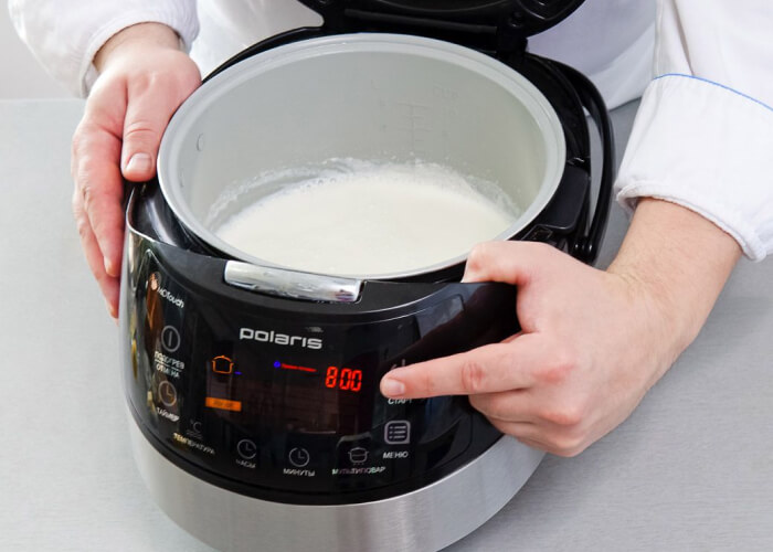 В мультиварку с баночками налейте теплой воды до уровня йогурта, закройте крышку и включите прибор в режиме «Йогурт».