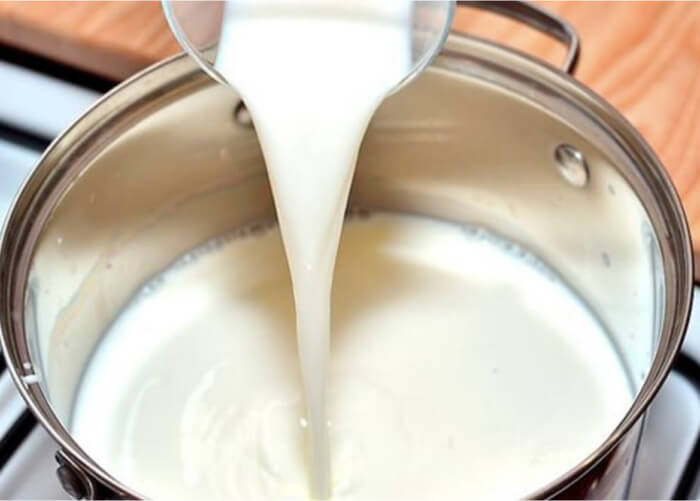 В эмалированную кастрюлю с толстым дном влейте молоко, поставьте его на плиту и нагрейте примерно до 30 градусов.
